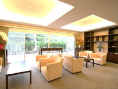 大きな窓の向こうに木々が見える共用ラウンジ。テーブルと、ソファが並んでおりくつろいだり談笑を楽しめる。