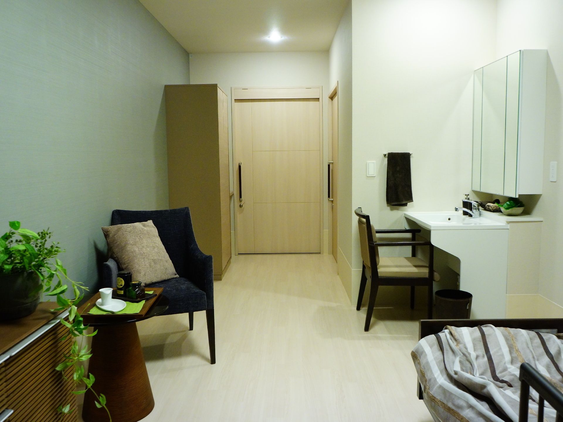 個室の扉には取っ手が付いているので、入室しやすくなっている。部屋にはベッド、タンス、観葉植物などが置かれている。