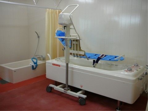 横になったまま入浴が可能な水色の機器が設置されている、機械浴室