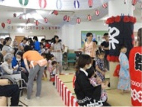 祭りの装飾が施された広い部屋に集まっている、スタッフや入居者様たち