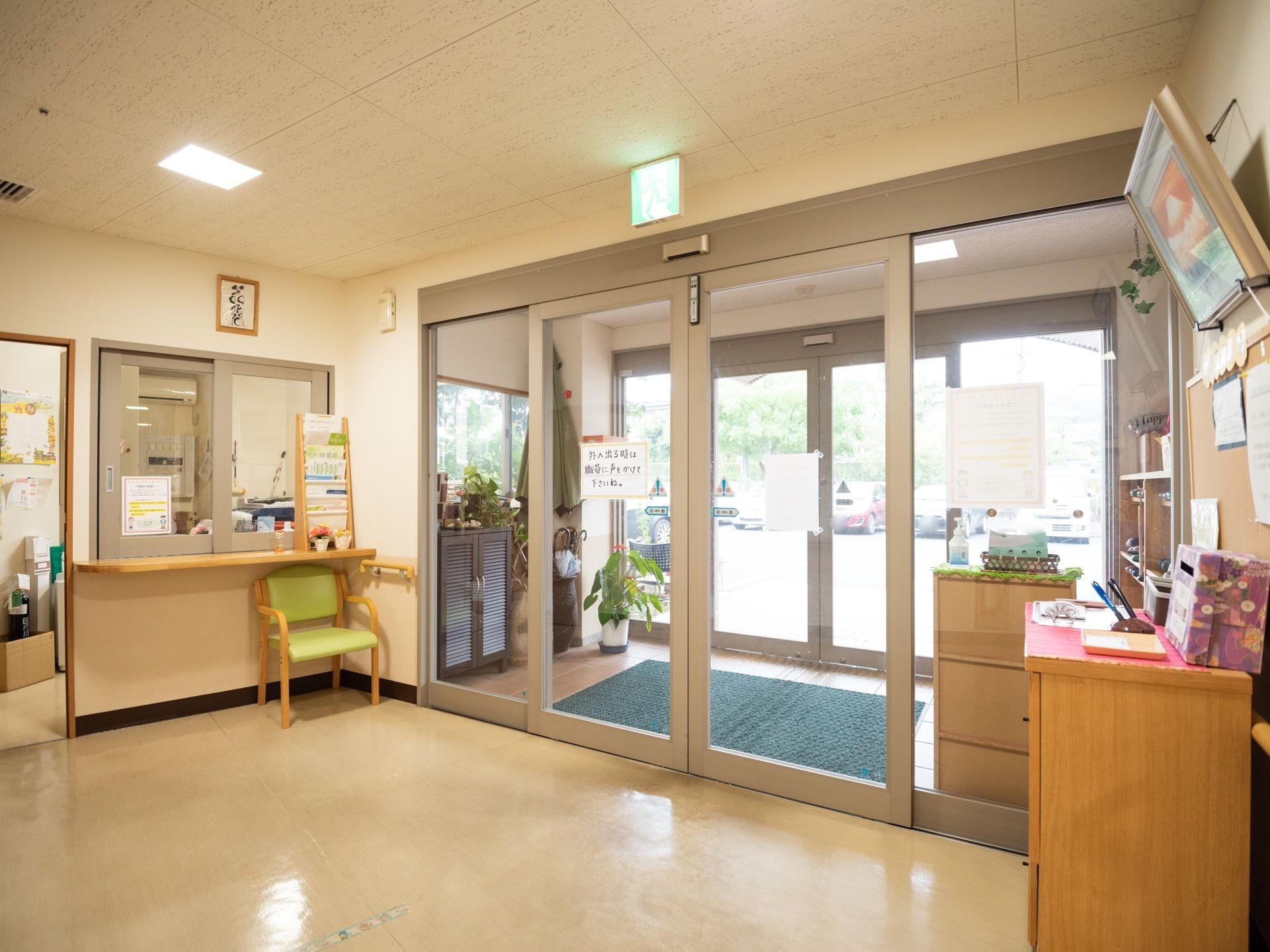 オートドアが設置された玄関である。床はフラットな造りで、間口も広い。受付にはカウンターがあり、椅子が置かれている。