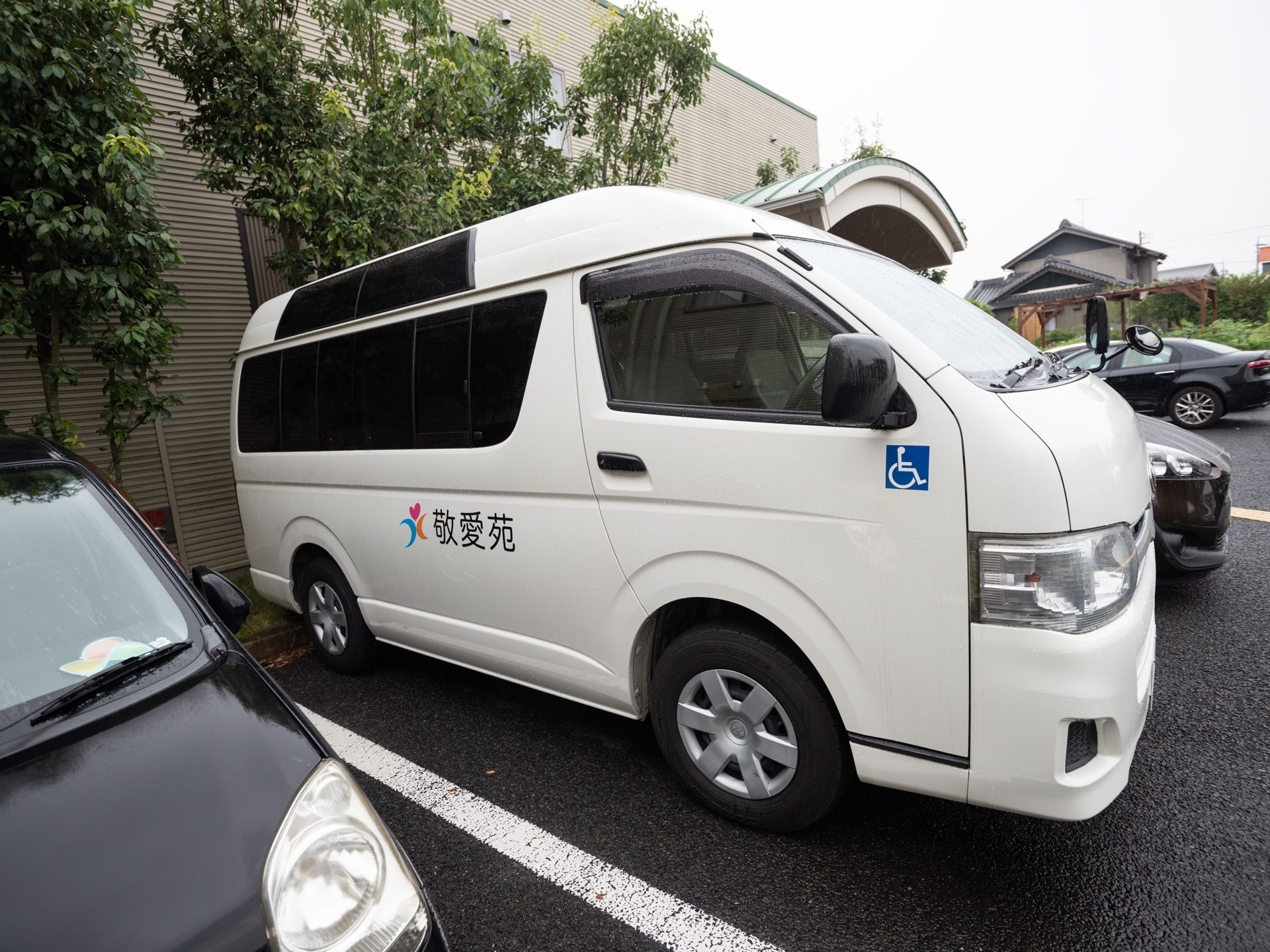 白の大型ワンボックスカーである。ボディに施設名が書かれ、障がい者マークが貼られている。後部座席は、黒のスモークを貼っている。