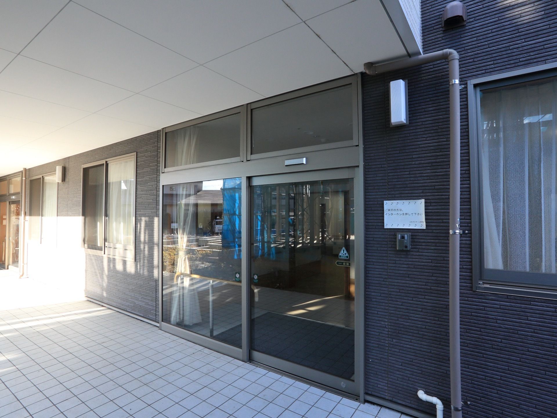 入り口の自動ドアは段差の無い、バリアフリー設計なので、どなたでも通りやすいような造りになっている。黒いシックな外観も特徴的である。