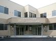 「ふるさとホーム綾瀬」の外観。木造2階建ての大きなクリーム色の施設を施している。