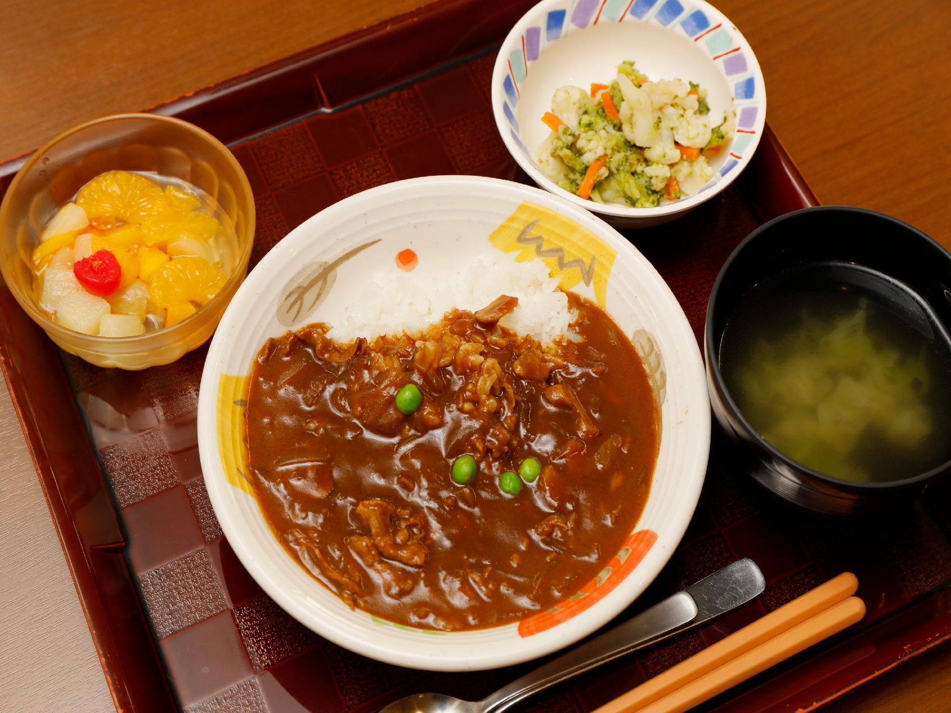 トレーに１人ずつのせて食事を提供している。箸のほかにスプーンを２つ添えており、食べやすいように考えられている。
