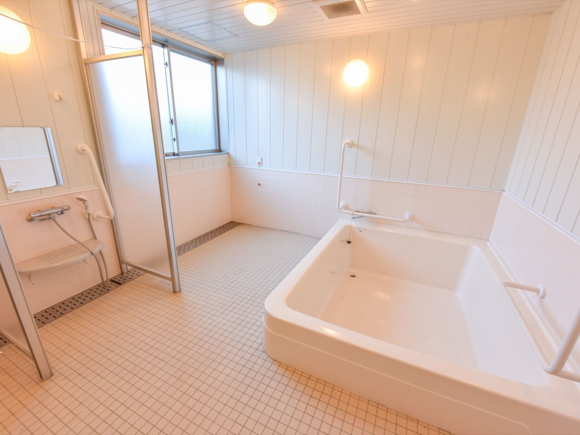 浴室は白を基調としている。広々とした浴槽の近くの壁には、手すりが２本ある。大きめの窓が付いており、換気が可能である。