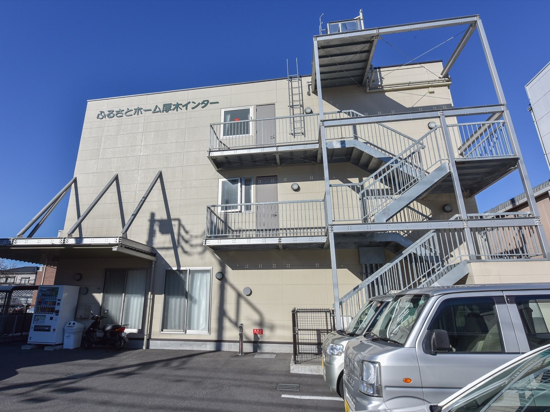 建物の駐車場側には、非常用の外階段が付いている。地上階の自動販売機がある場所には、屋根がありぬれずにドリンクを買うことができる。