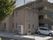 ベージュ基調の２階建ての建物の周囲には、看板と自動販売機が設置されている。隣接して駐車スペースが設けられている。