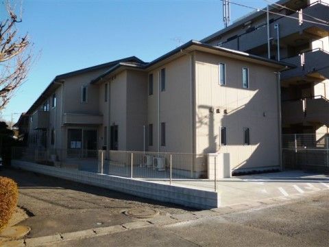 施設は２階建てで、ベージュ系の外壁には窓が多く設置されている。１階の玄関には屋根が設けられ、周囲はフラットな設計になっている。