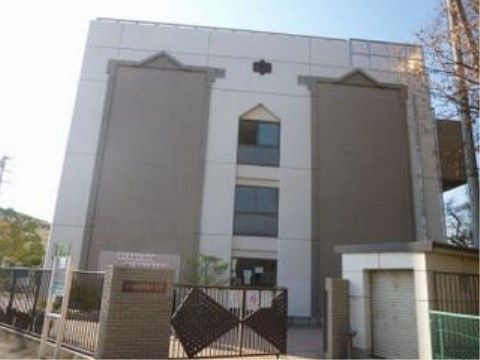 地域にある中学校の建物の外観である。鉄柵の付いた門を入ると４階建ての校舎があり、壁面には校章が見える。