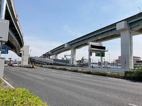 施設の近くには高速道路のインター入口がある。あまり車は走っておらず渋滞はしていない様子である。周囲に高い建物はほとんどない。