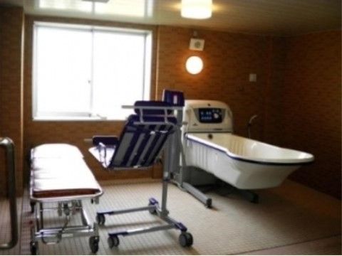 浴室の窓際の壁には丸い形の照明が設置されており、暖色系の色合いで温かみがあり落ち着いた雰囲気となっている。