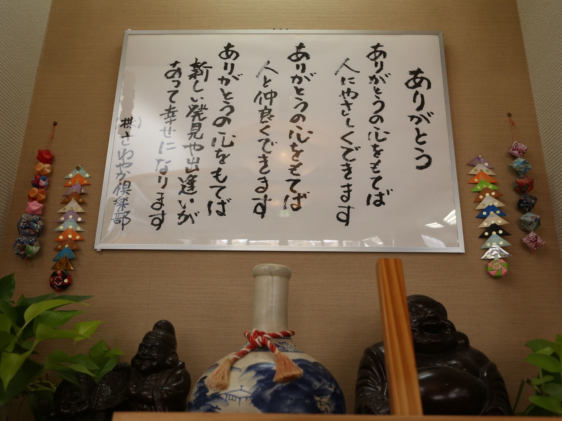 筆文字で詩が書かれた額や、折り紙で作った飾り物、つぼや布袋様の像などが飾られている。ポトスの鉢植えも一緒に置かれている。