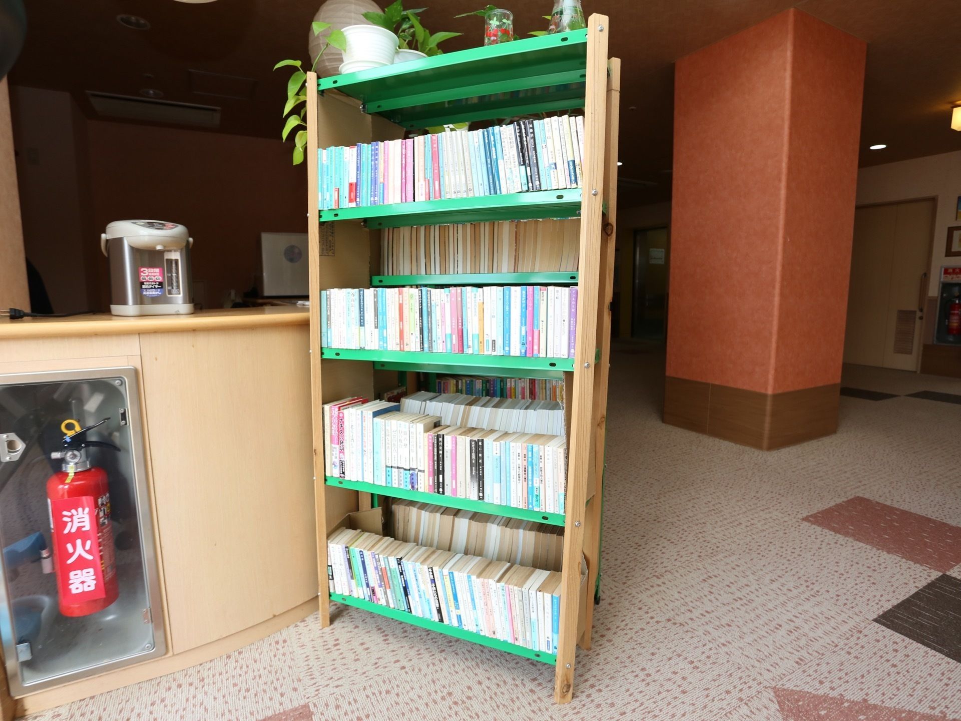 文庫や書籍が収納された棚が、共有スペースの半円カウンターの前に設置してある。本は入居者様に自由にお読みいただける。