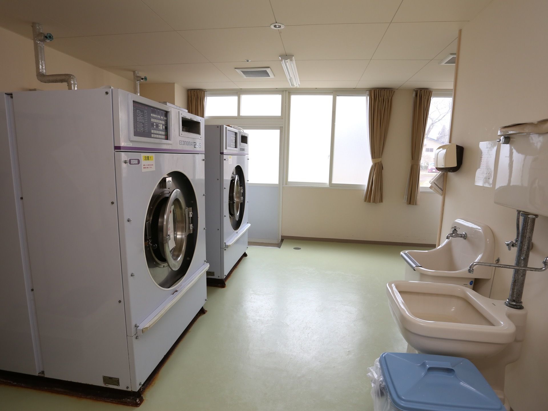洗濯室に業務用の大型洗濯乾燥機が並んでいる。共用で使うものや、入居者様の衣類などをここで洗濯していただける。