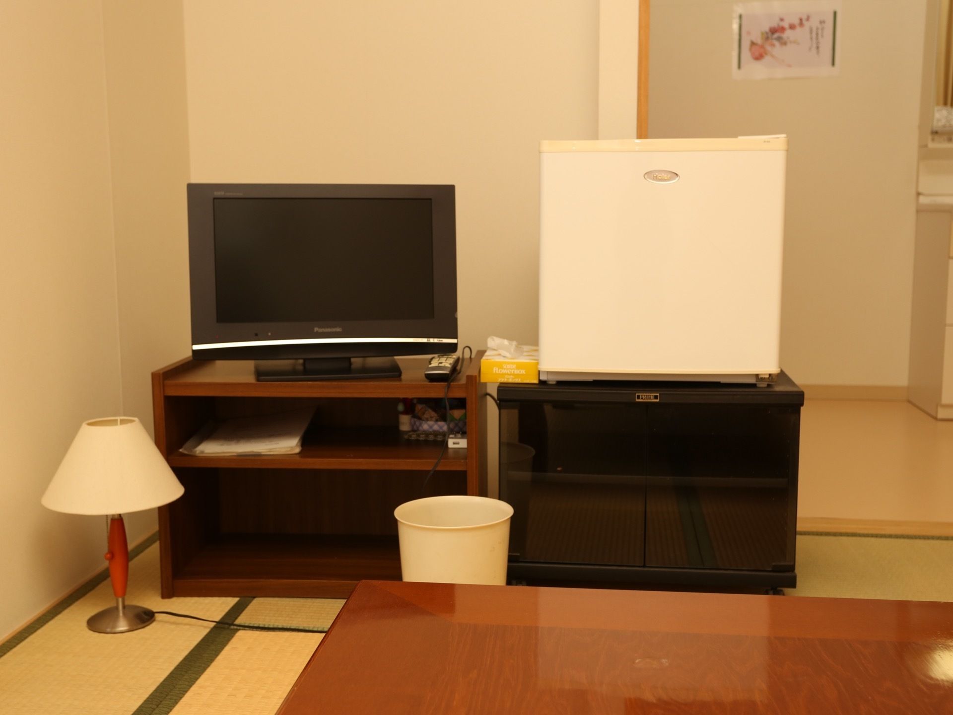 ほっとできる和室タイプの居室に、座卓、テレビ、ミニ冷蔵庫、スタンドなどが置いてある。水回りは板の間側にまとまっている。