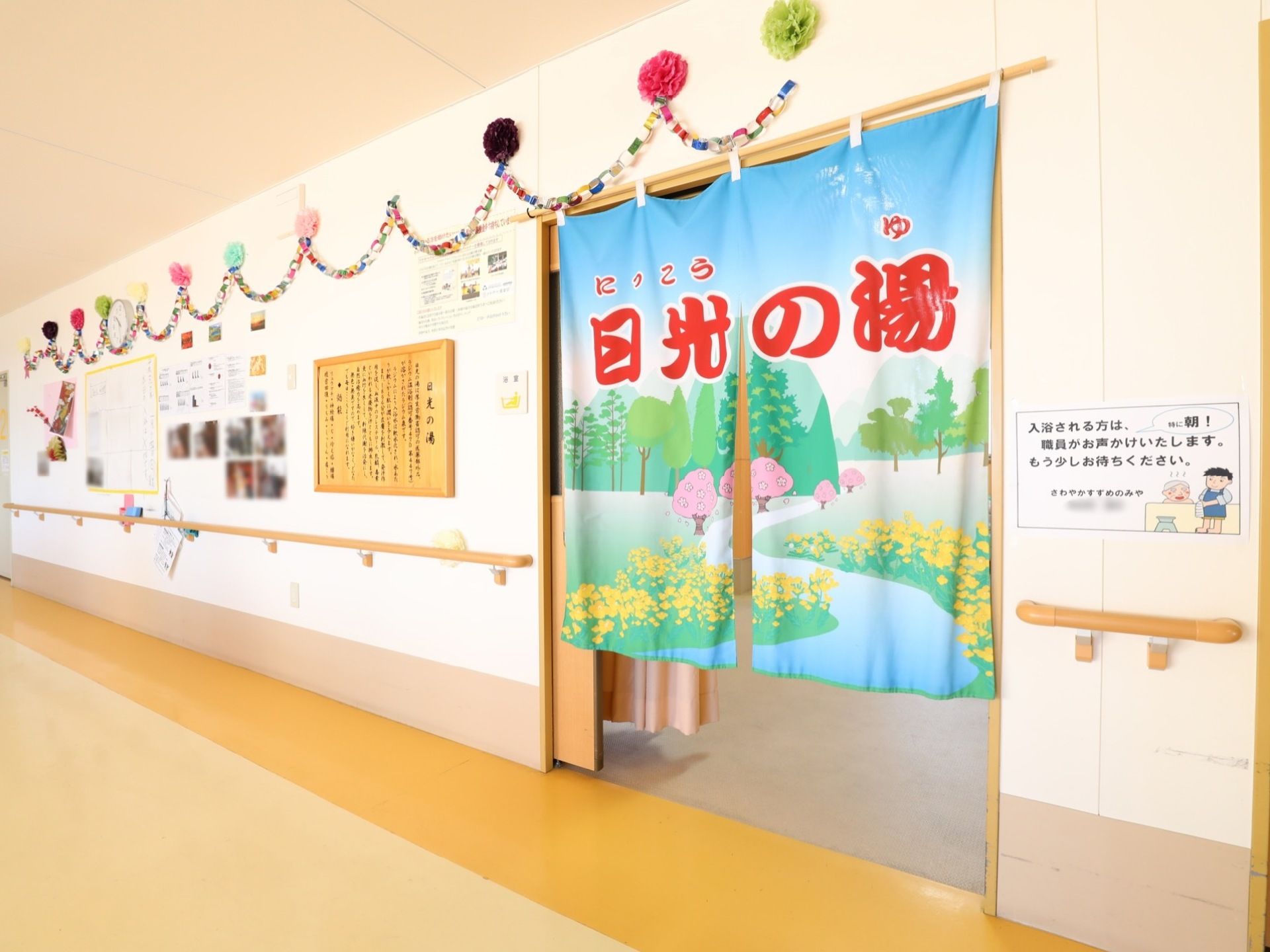浴室の入り口にはのれんがかけられている。周りの壁には飾りがレイアウトされており華やかな雰囲気になっている。