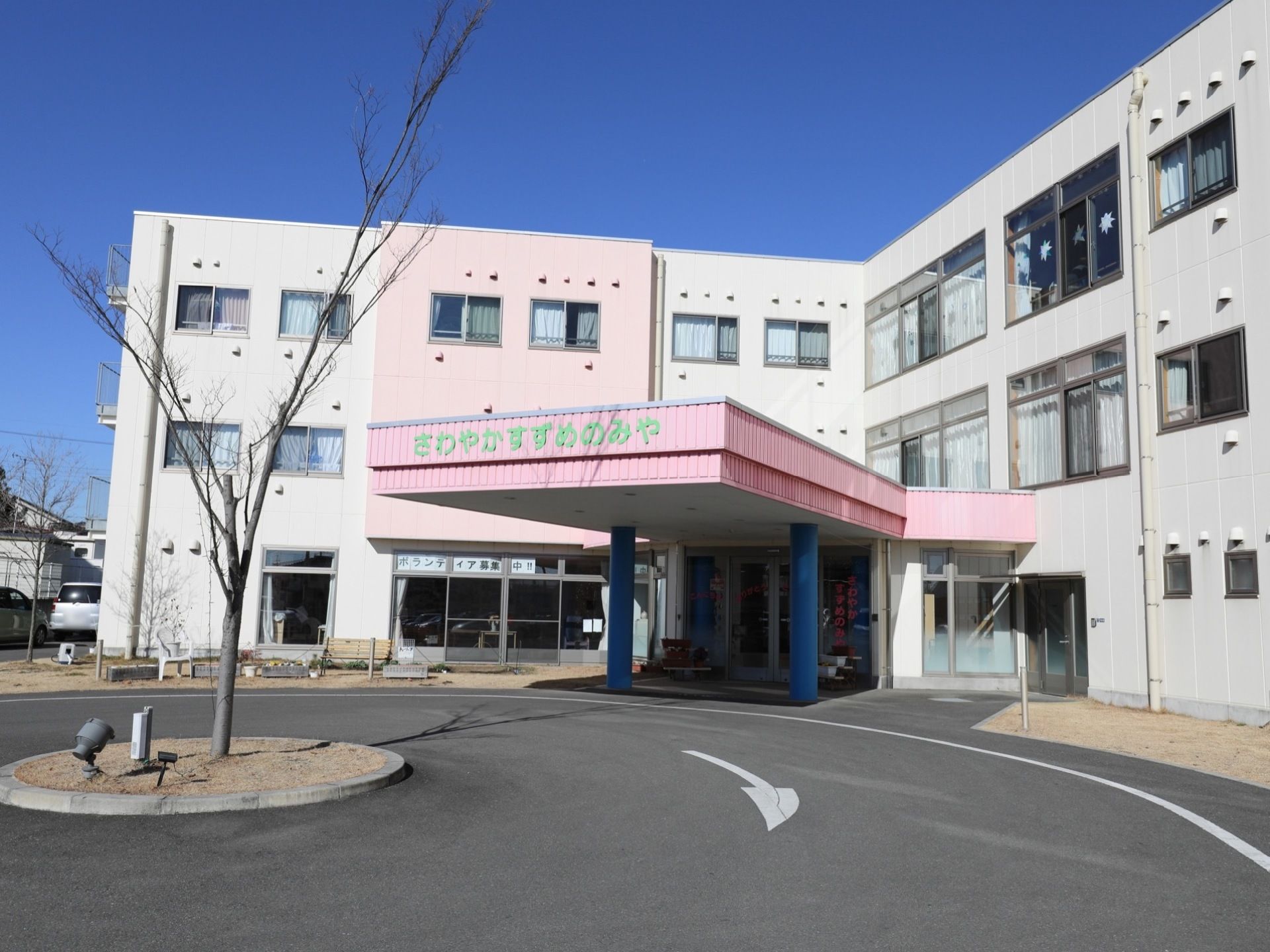 白い外壁とピンク色の玄関の屋根の建物になっており明るい雰囲気になっている。3階建てで、窓がたくさんので内部が明るい空間になっている。