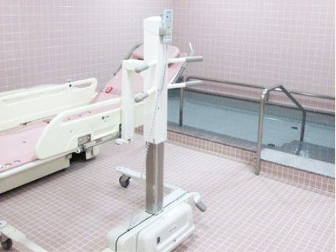 寝た状態のままでも入浴できる入浴用ベッドが設置された浴室である。手すりも完備され、安全に入浴できる浴槽がある。