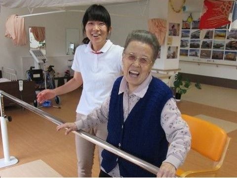 白衣を着た若い女性と一緒に、笑顔を見せている女性入居者様