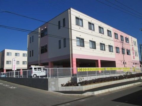 ピロティ式の建物で１階部分が駐車場である。白を基調にしており、一部ピンクや紫色でポップな建物である。