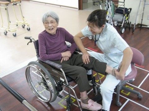 スタッフにサポートされながら、足のストレッチを行っている車椅子の女性