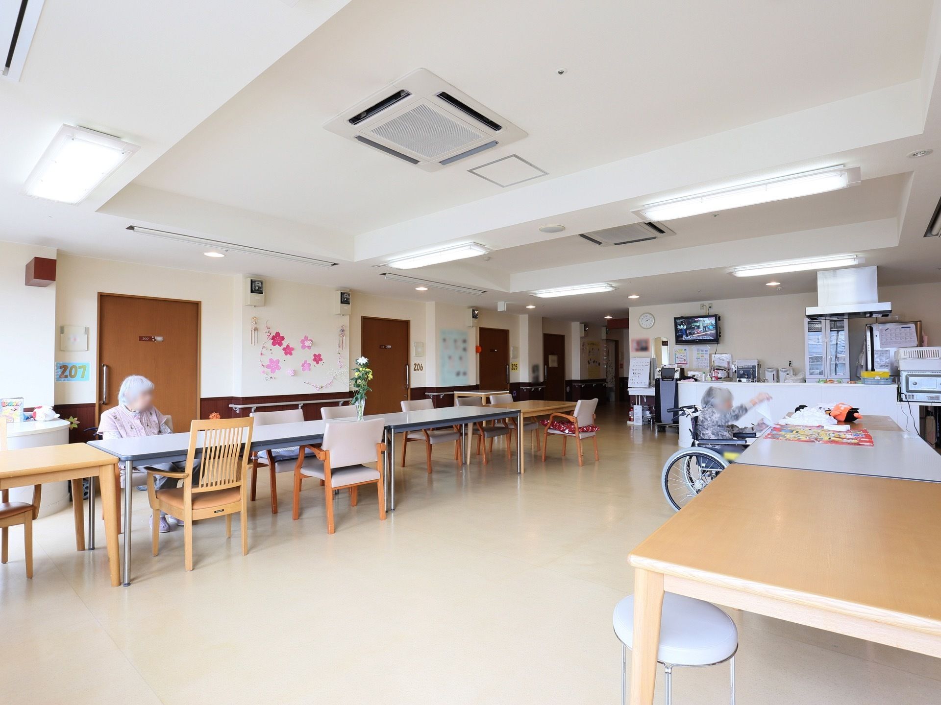 食堂に、テーブルがつなげて置かれている。入居者様が２名、それぞれ違うテーブルについている。奥にカウンターがある。