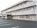 白い外壁の3階建ての施設の外観。施設前には大きな駐車場も完備されている。居室にはベランダもついている。