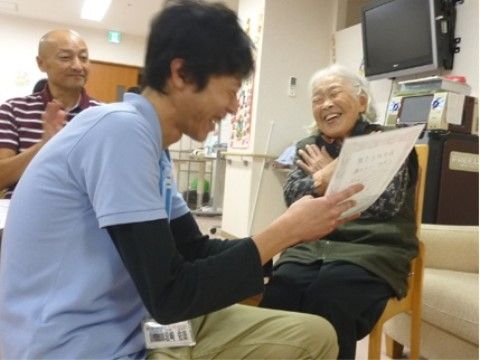水色のポロシャツを着た男性スタッフと談笑をする、入居者様の女性