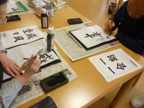 一期一会などの熟語を、筆と墨を使って書いている二名の入居者様