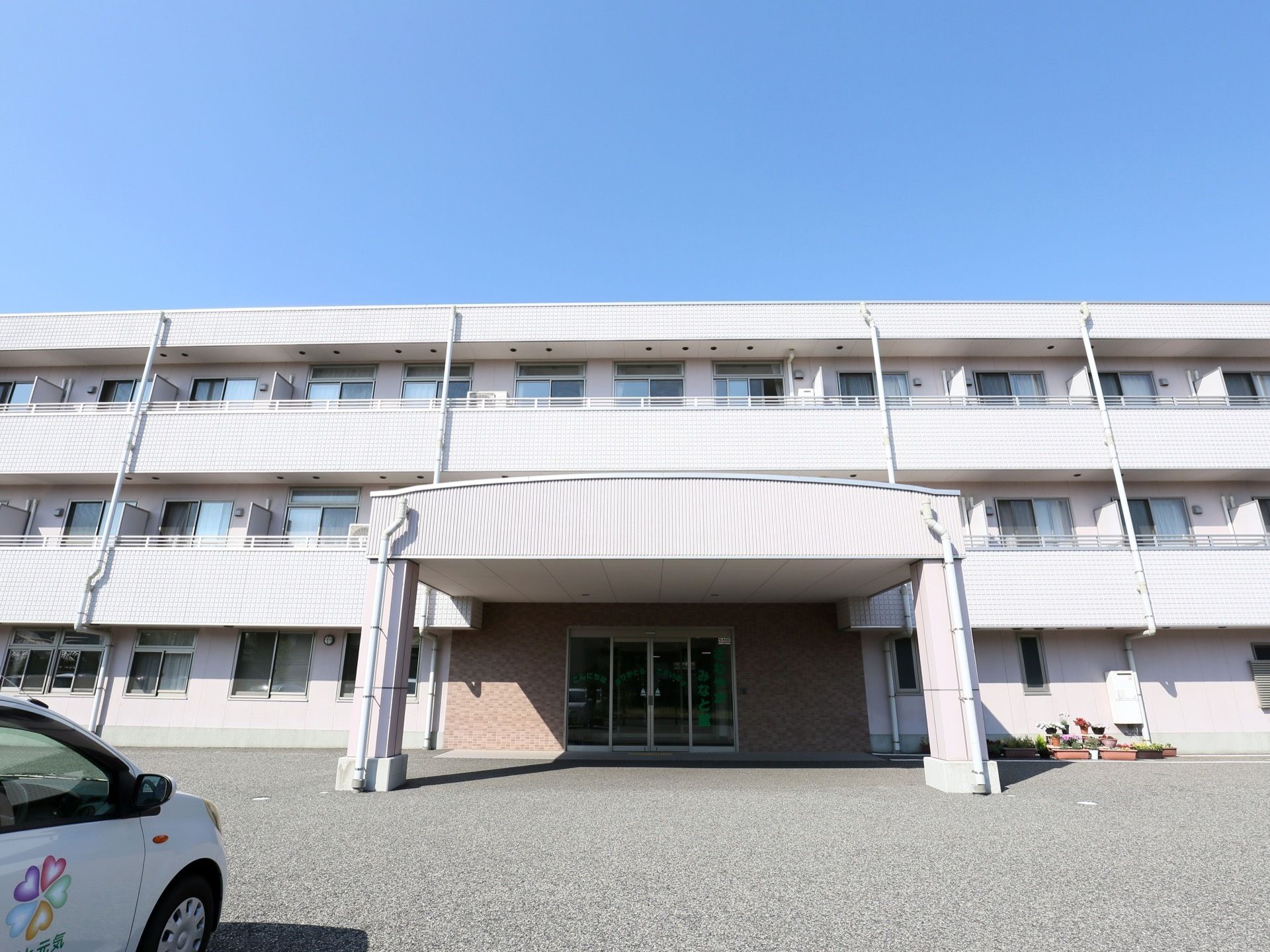 白色を基調とした、横に長い３階建ての施設である。玄関前には、屋根が少しアーチ状になっている車寄せがある。