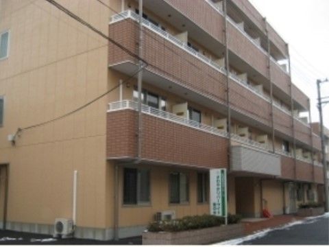 ブラウンのマンションタイプの建物は一見して住居のようで、施設である事を感じさせない。入り口の看板が目印である。