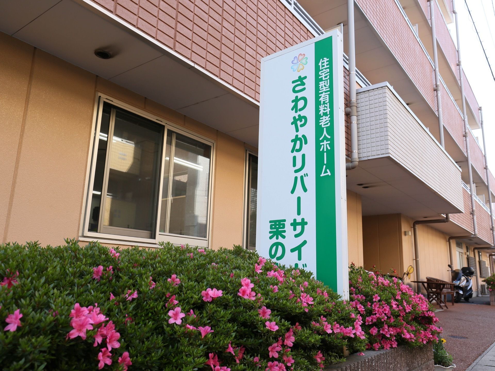 エントランスの外にある花壇に、施設名を記載した大きな銘板が建てられている。白と緑の色合いが爽やかな印象になっている。