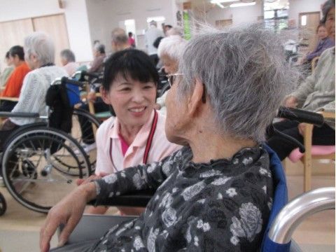 車椅子に座った入居者様と、同じ目線で話をしている女性スタッフ
