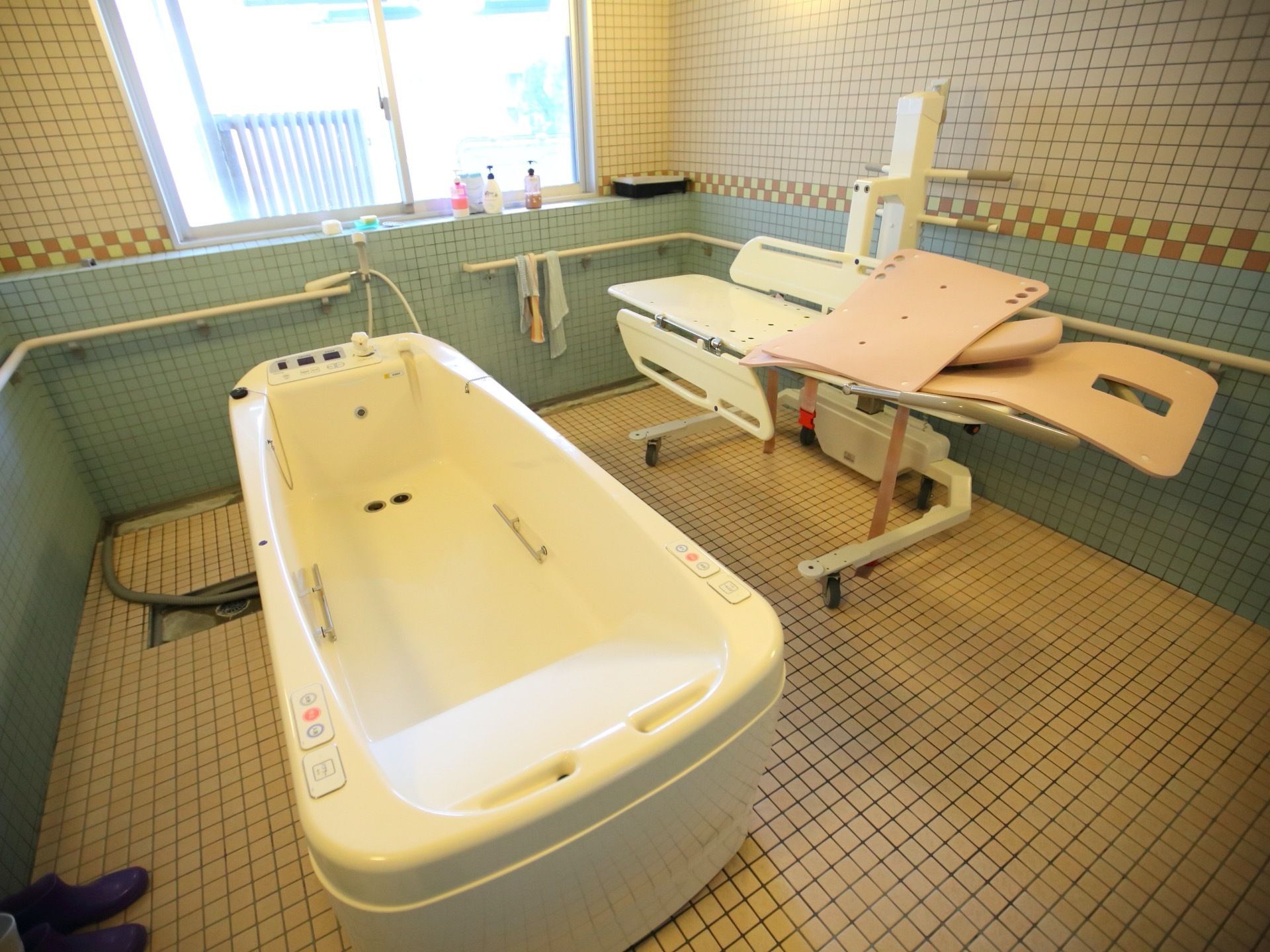 可動式のストレッチャーを備えた介護浴室がある。横になったままの状態でお湯につかることができる大きな浴槽が設置されている。