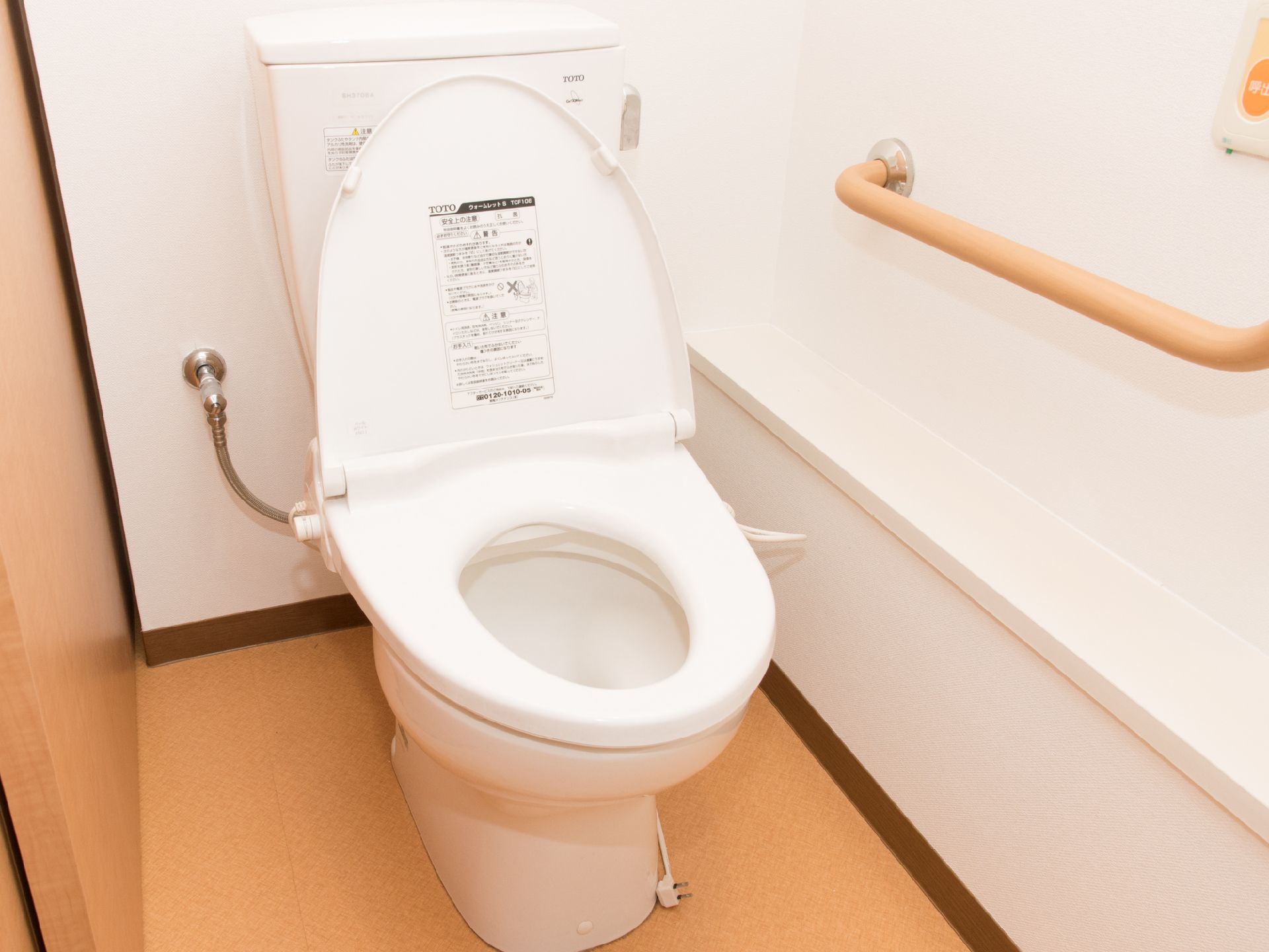 トイレは、白とベージュ系の色でまとめられたデザインになっている。壁には手すりや、ナースコールボタンが設置されている。