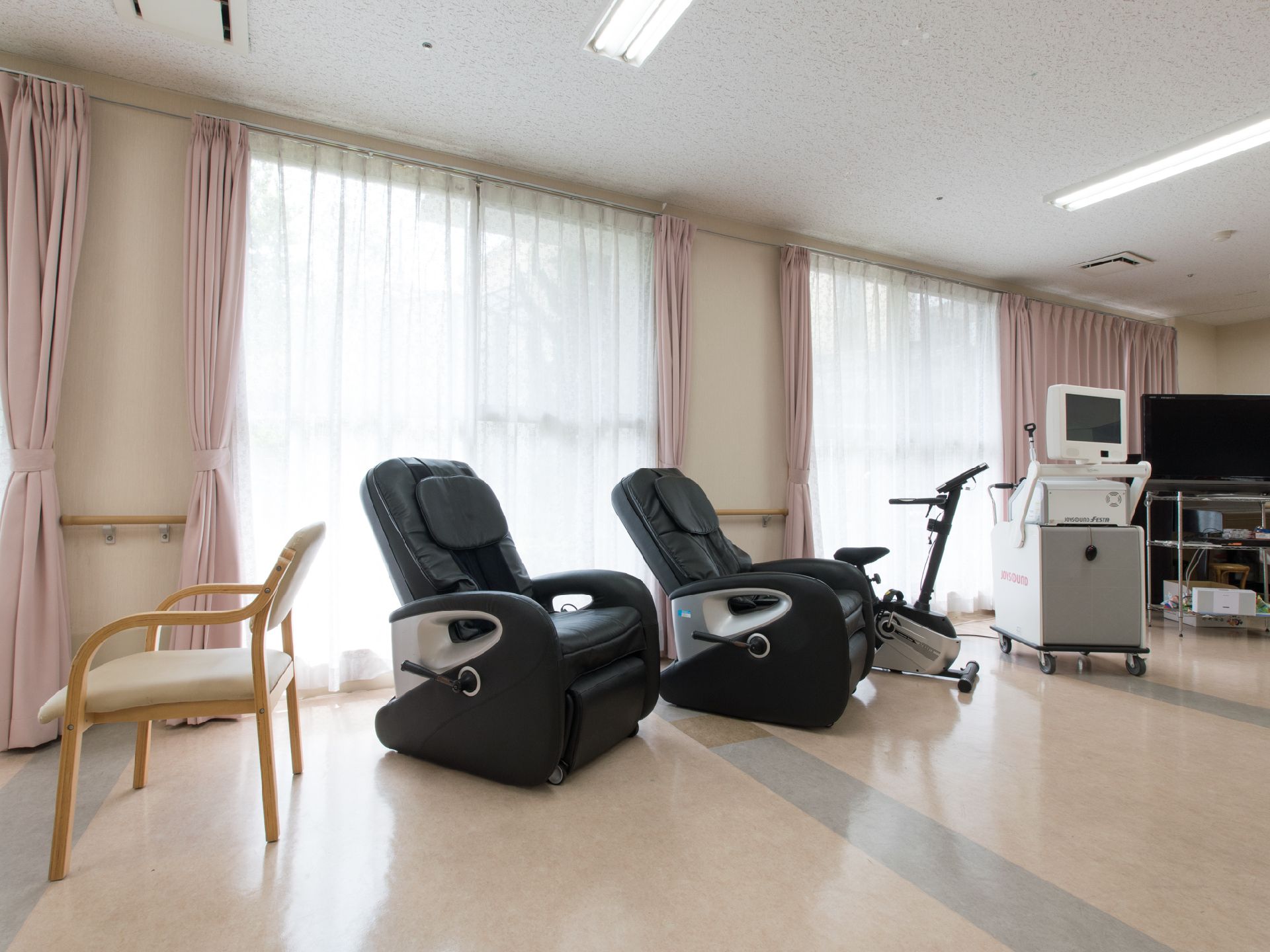 大きな窓のすぐ側のリハビリスペースには、サイクルマシーンが置いてある。どっしりとしたマッサージ用のソファーも2台置いてある。