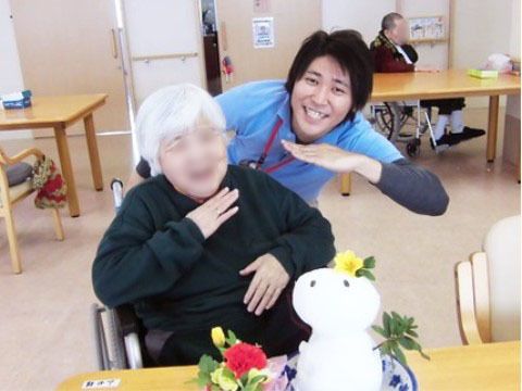 雪だるま風の小さなオブジェの前で、スタッフと同じポーズをとる女性入居者様