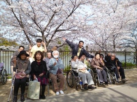 桜の木が立ち並んでいる河川敷で、ポーズをとる入居者様たち