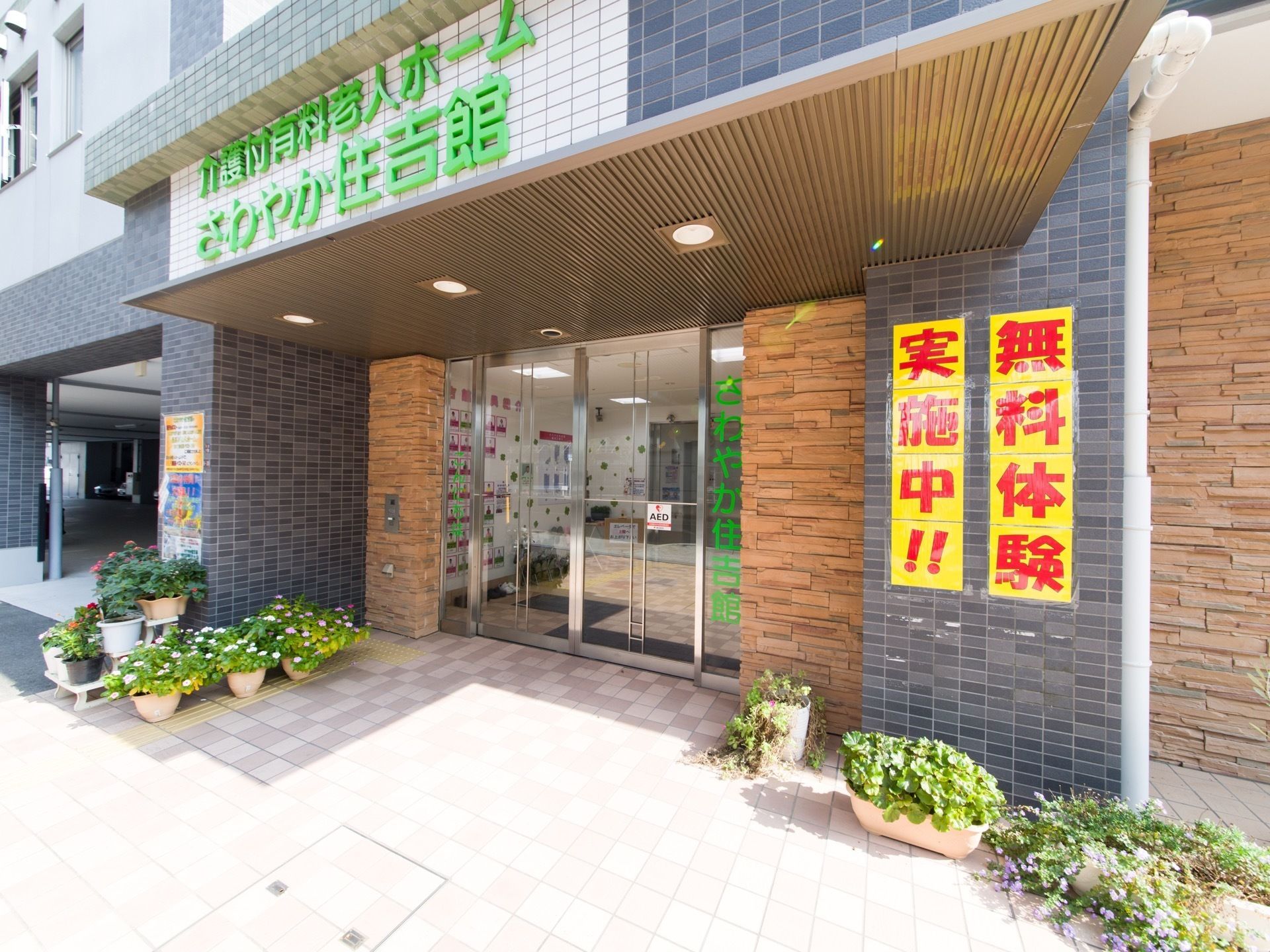 外に観葉植物を沢山飾っている。来訪者様が華やかな気持ちで入ってこれるよう工夫をしている。とても明るく開放的な雰囲気の施設。
