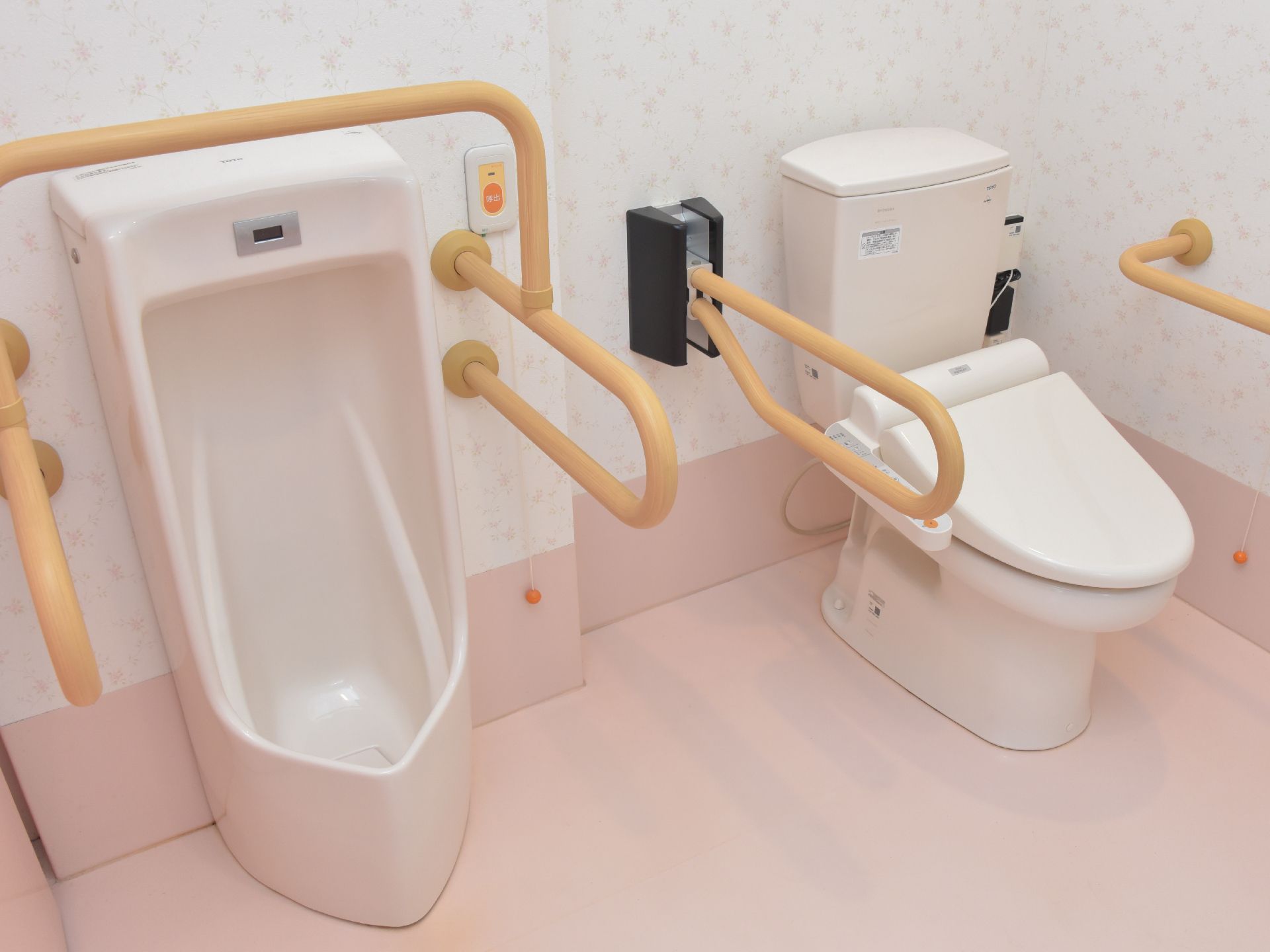 共用トイレは広々とした空間が確保されている。洋式トイレと男性用の小便器が並んでいる。壁には手すりも付いていて安心。