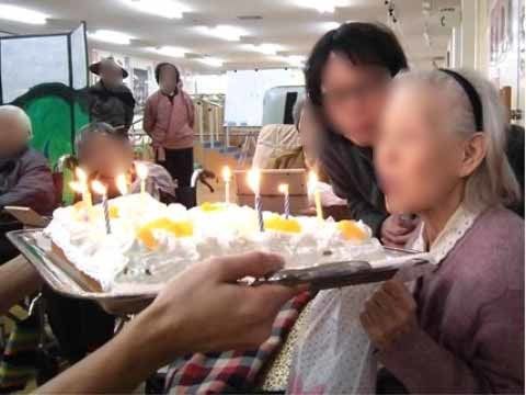 手作り風の生クリームたっぷりのケーキに立っているろうそくを吹き消す女性入居者様