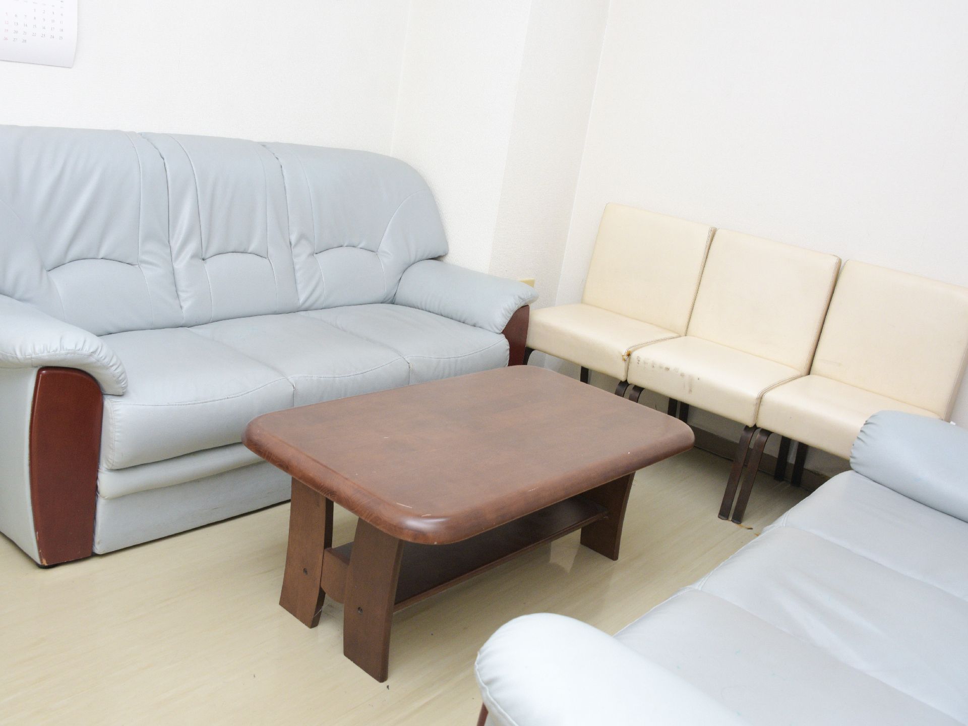 相談室には青い3人掛けのソファーが2脚と白い3人掛けのソファーが1脚、中央に木目調のテーブルが置かれている。