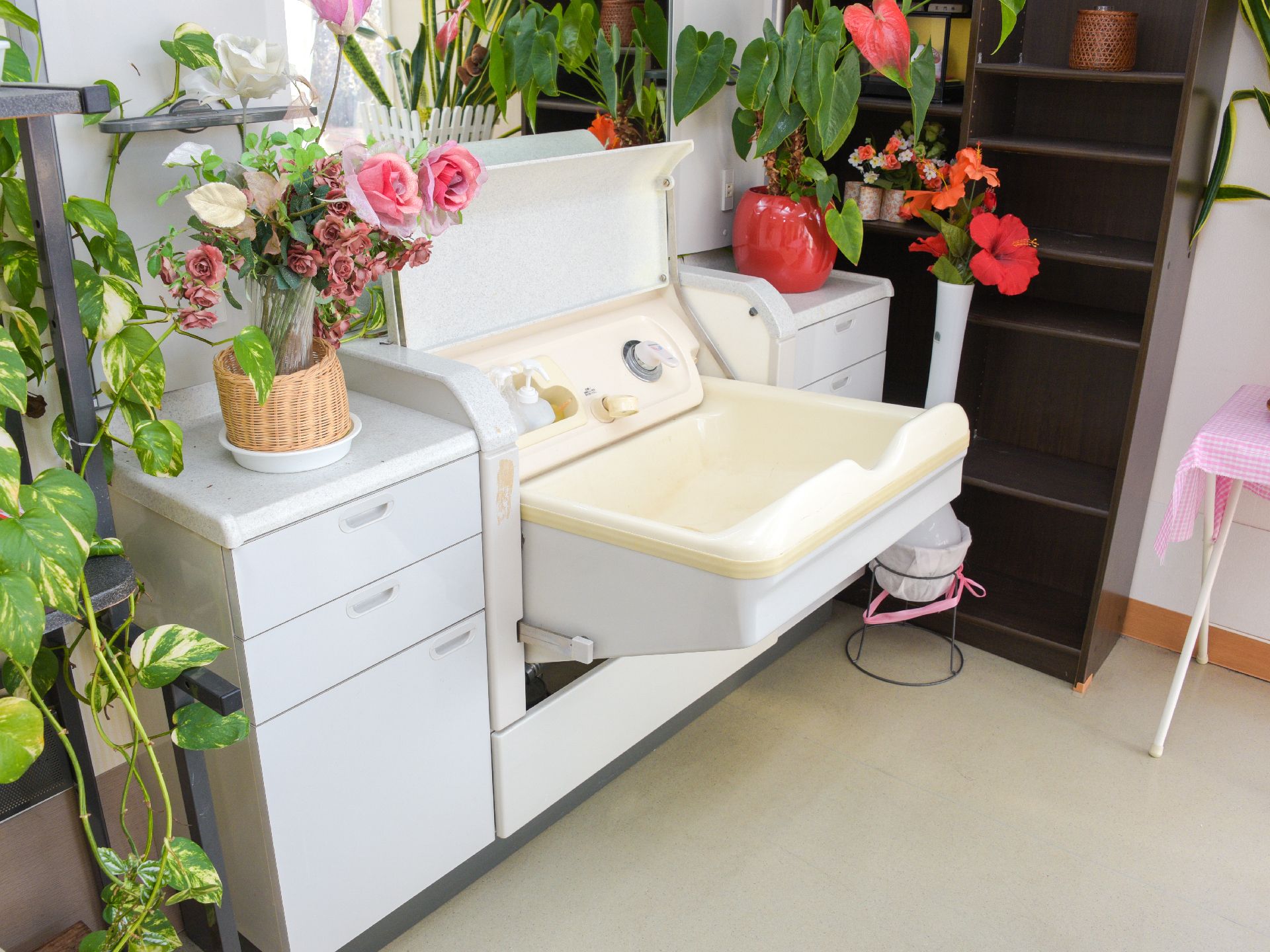 座ったままで頭を洗うこともできる洗面台。周りには暖色系の赤やピンクの造花が置かれ、華やかになっている。