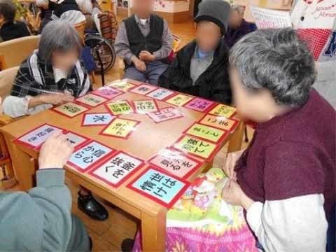 正方形のテーブルの上にカルタが並べられている。カルタの文字は入居者様が見やすいように大きくなっている。