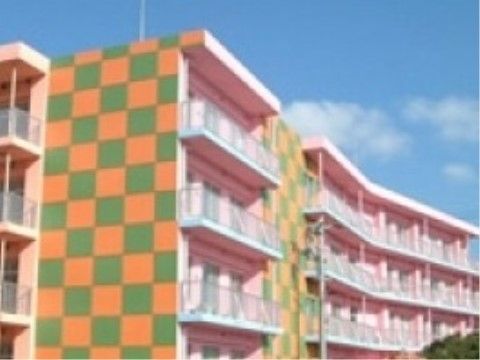 施設の外壁の横側はオレンジ色と黄緑色のチェック柄で、カラフルな外観になっている。その他の外壁はピンク色である。
