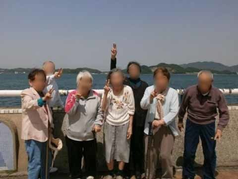 外出時に海をバックにポーズをとっている七名の入居者様