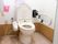 白とピンク基調のトイレである。手すりは、立ち上がる時に安心である。ウォシュレットも付いているので、快適に使用できる。