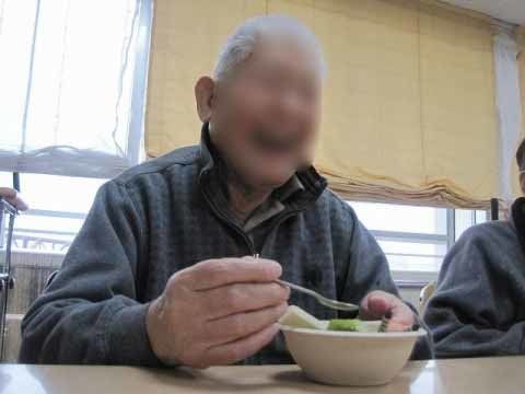 盛り付けられた食事を、スプーンを片手に笑顔で楽しむ入居者様の男性