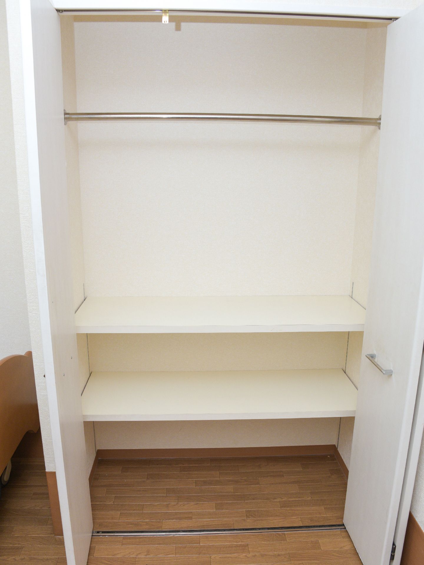 白木で作られたクローゼット。上半分がコート掛けになっており、下半分は棚になっているため、収納力が高い。